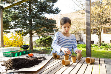 Girl filling nursery pots with soil - LVF08792