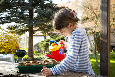 Girl watering plants in her little greenhouse - LVF08800