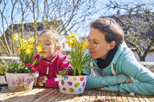 Mutter und Tochter riechen an Blumen auf dem Balkon - DIKF00446