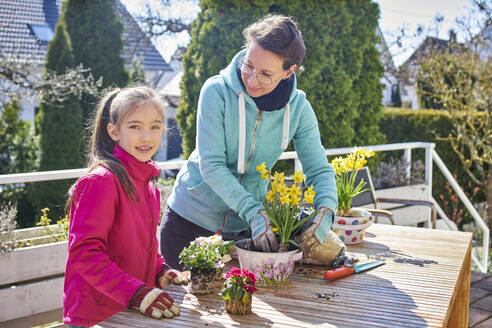 Mutter und Tochter pflanzen gemeinsam Blumen auf dem Balkon - DIKF00451