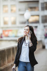 Portrait of happy woman on the phone walking in the city - LJF01504