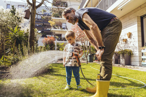 Father and son watering the lawn in garden - MFF05568