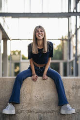 Young blond woman sitting on a wall - MPPF00760