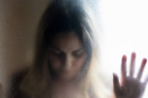 Porträt einer reifen Frau mit geschlossenen Augen hinter einer Glasscheibe, lizenzfreies Stockfoto