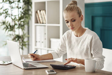 Businesswoman Using Laptop At Desk In Office - EYF04240