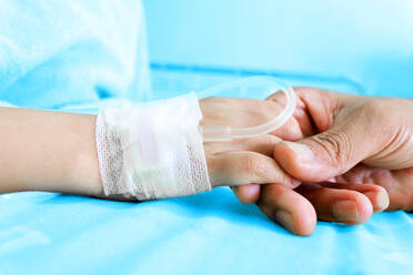 Nahaufnahme einer Hand, die einen Patienten am Krankenhausbett hält - EYF04287