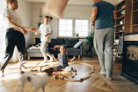 Little girl meditating in the middle of toys, while family are running around her stock photo