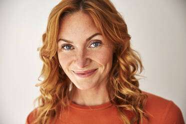 Portrait of smiling red-haired woman looking at camera - JHAF00082