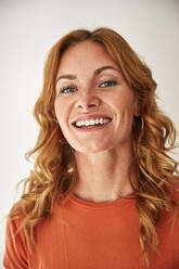 Portrait of smiling red-haired woman looking at camera - JHAF00083