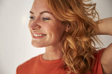 Portrait of red-haired woman, hand in hair, looking sideways - JHAF00085