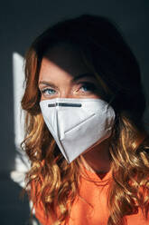 Portrait of red-haired woman wearing a FFP2 mask at home - JHAF00087