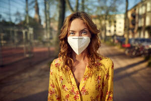 Rothaarige Frau mit einer FFP2-Gesichtsmaske in der Stadt - JHAF00100