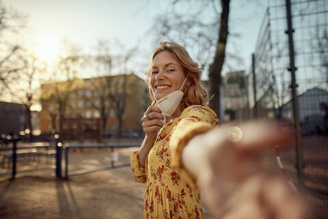 Rothaarige Frau mit einer FFP2-Gesichtsmaske in der Stadt, lizenzfreies Stockfoto