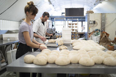 Man and woman preparing little loaves of bread in bakery - FBAF01470