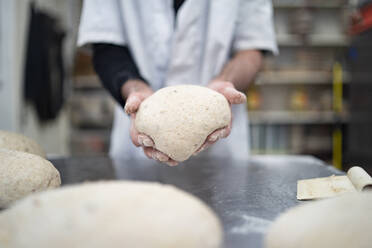 Nahaufnahme eines Bäckers bei der Zubereitung von Brot in einer Bäckerei - FBAF01482