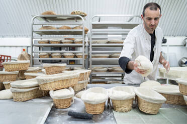 Bäcker legt Teig in den Korb in einer Bäckerei - FBAF01493