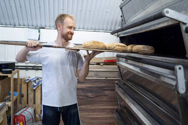 Bäckerin backt kleine Brote in einer Bäckerei - FBAF01495