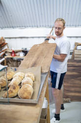 Bäckerin backt kleine Brote in einer Bäckerei - FBAF01496