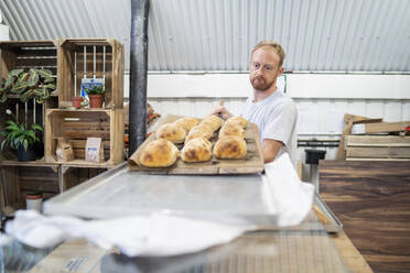 Bäckerin backt kleine Brote in einer Bäckerei - FBAF01497