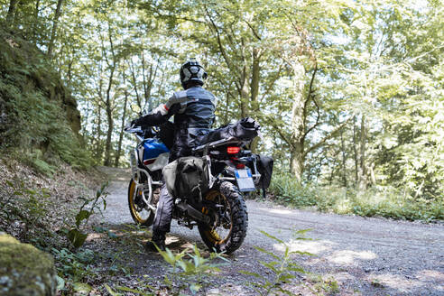 Motorradfahrer bei einer Fahrt auf einem Waldweg - FBAF01503