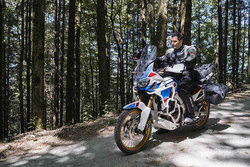 Motorradfahrer bei einer Fahrt auf einem Waldweg - FBAF01510