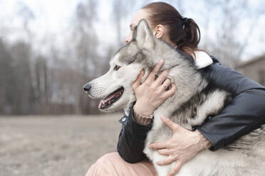 Frau, die ihren Hund umarmt - EYAF01026