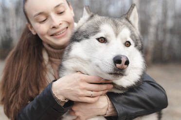 Frau kuschelt mit ihrem Husky - EYAF01031