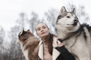 Porträt einer Frau mit zwei Huskys, die etwas beobachten - EYAF01039