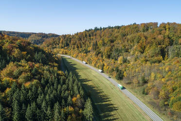 Deutschland, Baden-Württemberg, Heidenheim an der Brenz, Drohnenaufnahme des Verkehrs auf der Autobahn entlang des herbstlichen Waldrandes - RUEF02815