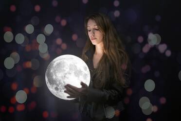 Digital Composite Image Of Young Woman Holding Full Moon - EYF04334