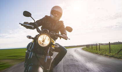 Porträt eines reifen Mannes, der auf einer Straße Motorrad fährt - EYF04422