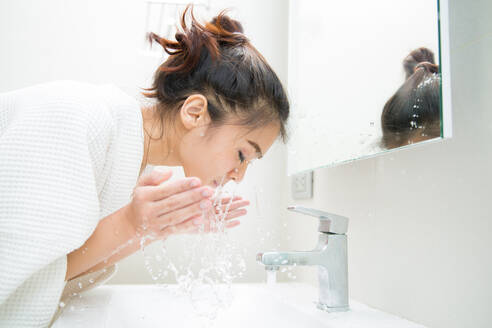 Seitenansicht der jungen Frau Waschen Gesicht im Badezimmer zu Hause - EYF04443