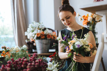 Frau arrangiert Blumen im Geschäft - EYF04445