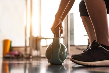 Low Section Of Woman Lifting Kettlebell At Gym - EYF04464