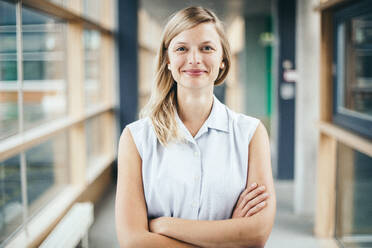 Portrait Of Confident Woman With Arms Crossed Standing In Lobby - EYF04486