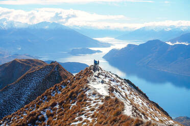 Distant View of Wanderer stehend auf Klippe gegen See im Winter - EYF04507