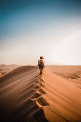 Rear View Of Woman Walking On Sand Dune In Desert - EYF04509