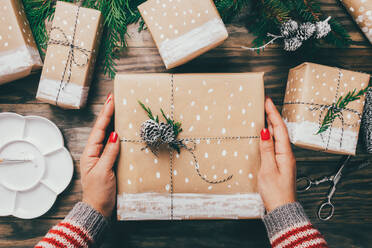 High Angle View Of Woman Holding Christmas Present On Table - EYF04554