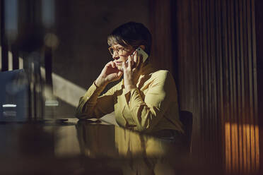 Geschäftsfrau, die in ihrem nachhaltigen Büro sitzt und telefoniert - MCF00645