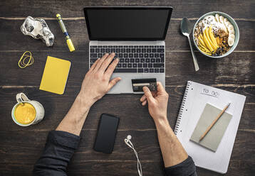 Overhead view of man holding credit card in home office - MSUF00269