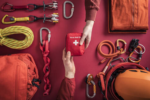 Overhead view of woman handing over first aid kit to man with climbing equipment in background - MSUF00279