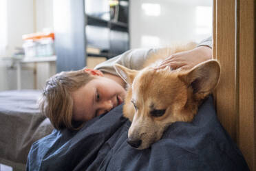 Boy lying on bed stroking his dog - VPIF02320