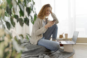 Junge Frau benutzt Smartphone zu Hause - AFVF06008