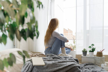 Young woman at home looking out of window - AFVF06015