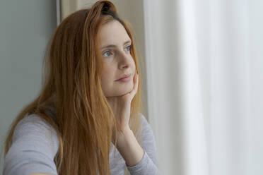 Portrait of serious young woman looking out of window - AFVF06030
