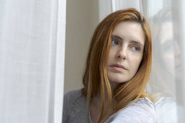 Portrait of serious young woman looking out of window - AFVF06031