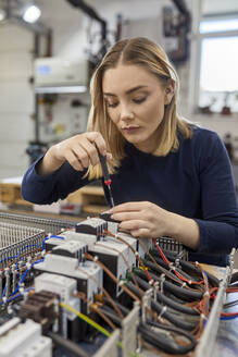 Female electrician working on circuitry in workshop - ZEDF03214