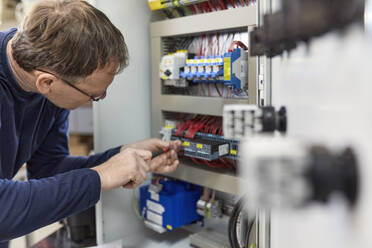 Elektriker bei Arbeiten an Schaltkreisen in der Werkstatt - ZEDF03224