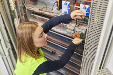 Female electrician working with voltmeter at fuse box - ZEDF03233