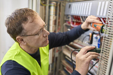 Electrician working with voltmeter at fuse box - ZEDF03234